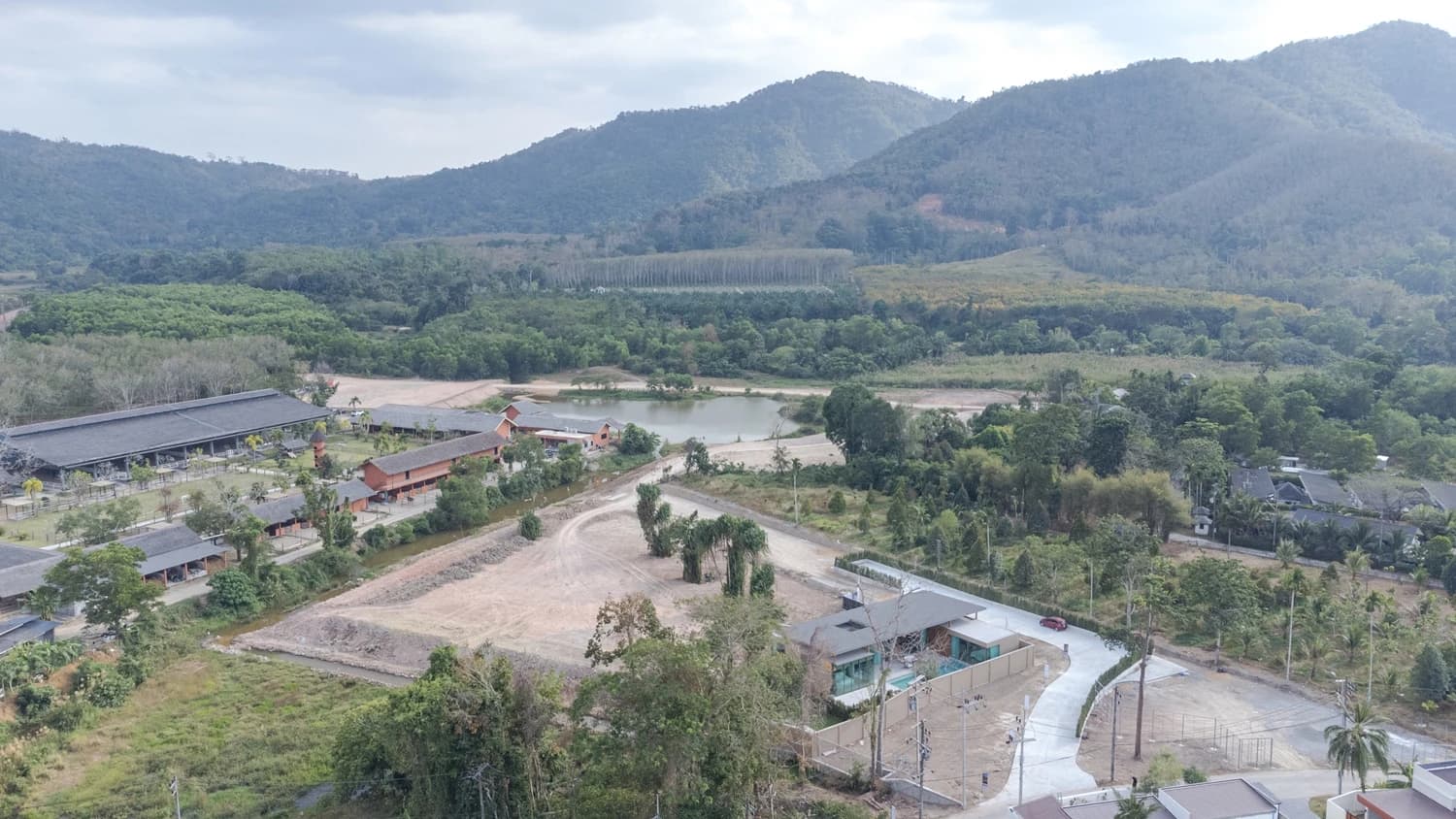 Drone view towards the forested Kamala range and the Bang Neow Dum reservoir, villa A1 in the foreground